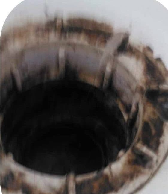 The inside of a cooker extractor housing, coated in baked-on brown and black grease